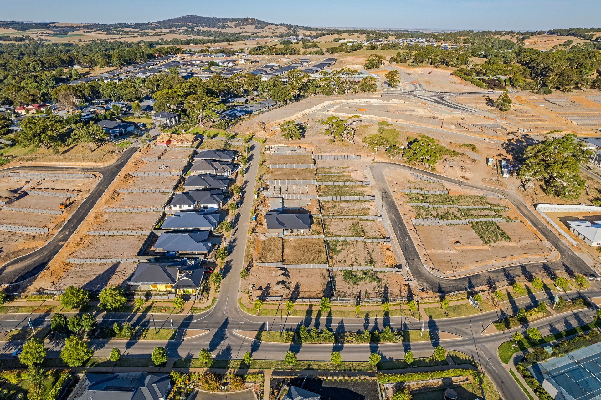 Aerial view display homes surrounded by construction earthworks preparing for new dwellings.